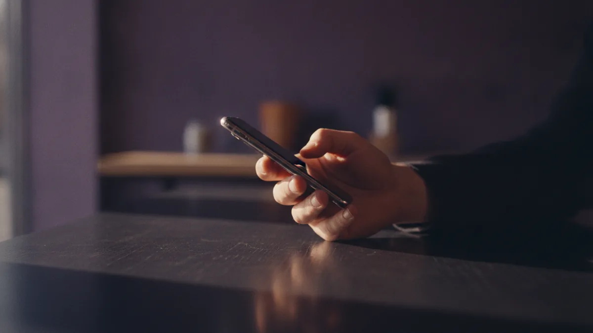 Person holding a phone outdoors, representing personal identity