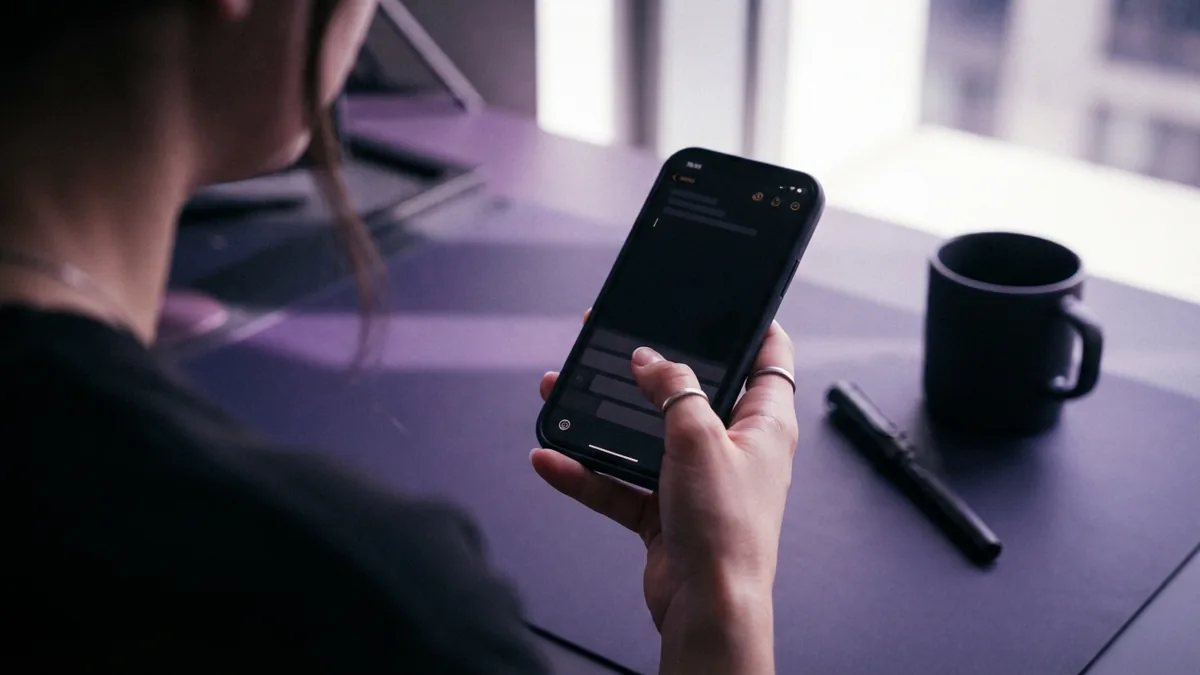 Hand editing a short TikTok profile bio on a smartphone at a tidy desk
