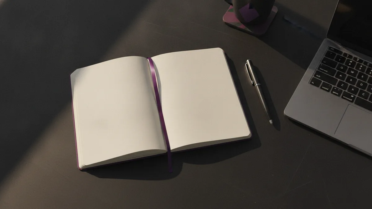 Notebook and pen beside a laptop, planning a clear bio structure
