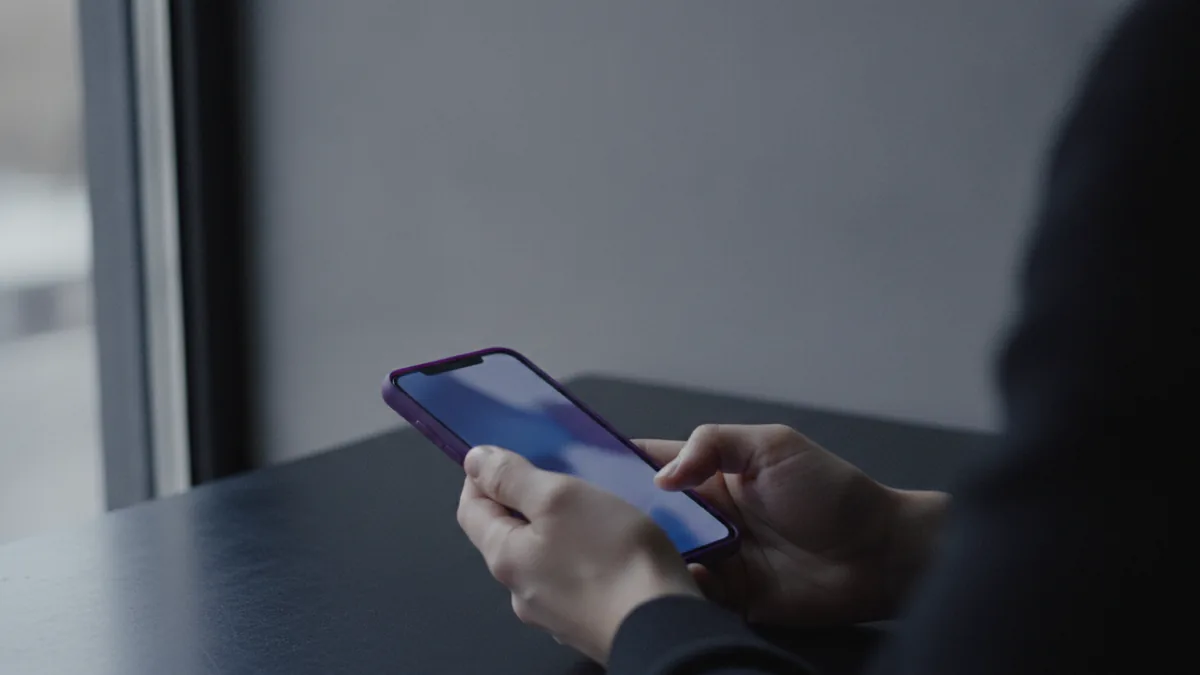 Hands checking a phone near a window, signaling quick first impressions