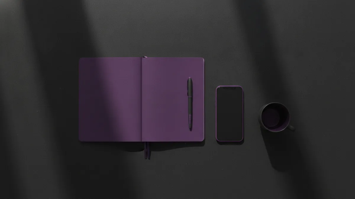 Notebook and pen beside a phone for drafting a short Instagram bio