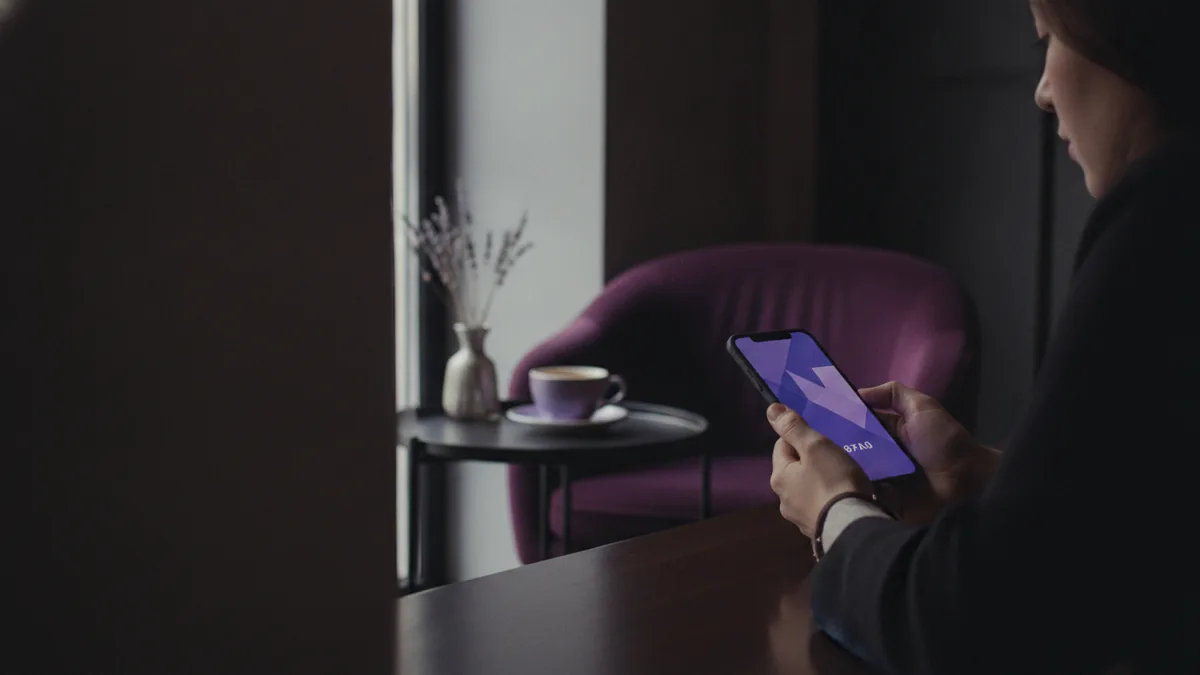 Person in a cafe checking their phone with a personal, calm vibe.